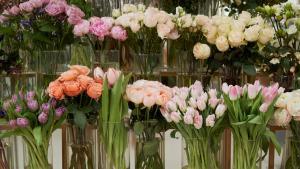 A display of flowers in vases on a shelf in a цветочный магазин.